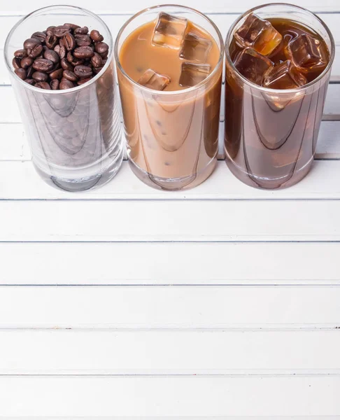 Ahşap arka plan üzerinde siyah kahve, soğuk latte ve fasulye buzlu