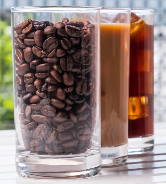 Black iced coffee, cold latte, and beans over wooden background