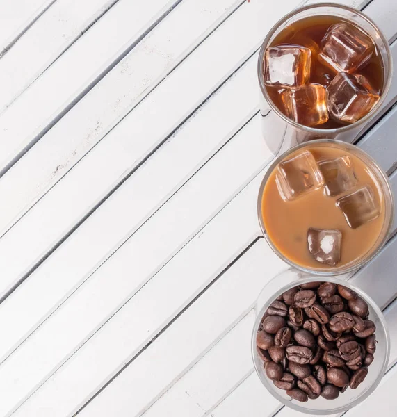 Black iced coffee, cold latte, and beans over wooden background