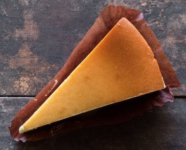 Ahşap masa üstüne peynir pasta bir dilim