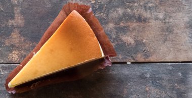 Ahşap masa üstüne peynir pasta bir dilim