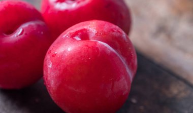 Koyu ahşap arka plan üzerinde kırmızı erik