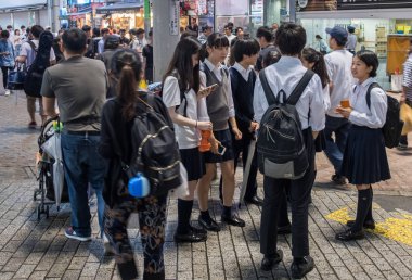Tokyo, Japonya - 23 Haziran 2018. Japon lise öğrencisi Shibuya sokakta geceleri dışarı asılı.