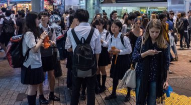 Tokyo, Japonya - 23 Haziran 2018. Japon lise öğrencisi Shibuya sokakta geceleri dışarı asılı.