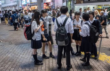 Tokyo, Japonya - 23 Haziran 2018. Japon lise öğrencisi Shibuya sokakta geceleri dışarı asılı.