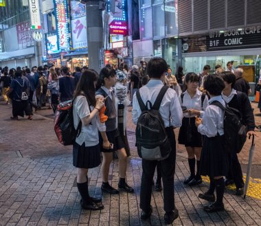 Tokyo, Japonya - 23 Haziran 2018. Japon lise öğrencisi Shibuya sokakta geceleri dışarı asılı.