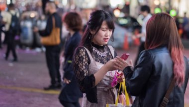 Tokyo, Japonya - 23 Haziran 2018. Hachiko Meydanı, Shibuya geceleri'akıllı telefon kullanan Japon kız.