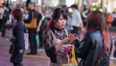 Tokyo, Japonya - 23 Haziran 2018. Hachiko Meydanı, Shibuya geceleri'akıllı telefon kullanan Japon kız.