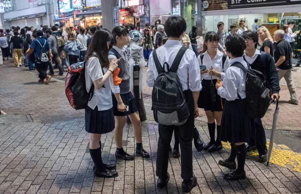 Tokyo, Japonya - 23 Haziran 2018. Japon lise öğrencisi Shibuya sokakta geceleri dışarı asılı.
