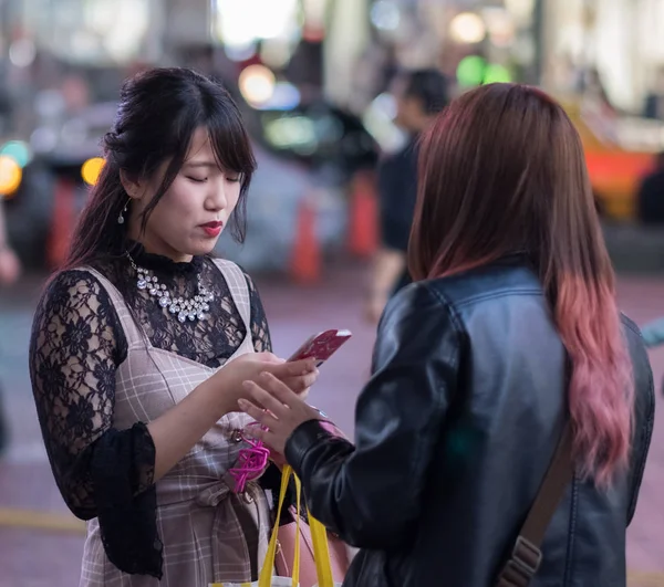 Tokyo, Japonya - 23 Haziran 2018. Hachiko Meydanı, Shibuya geceleri'akıllı telefon kullanan Japon kız.