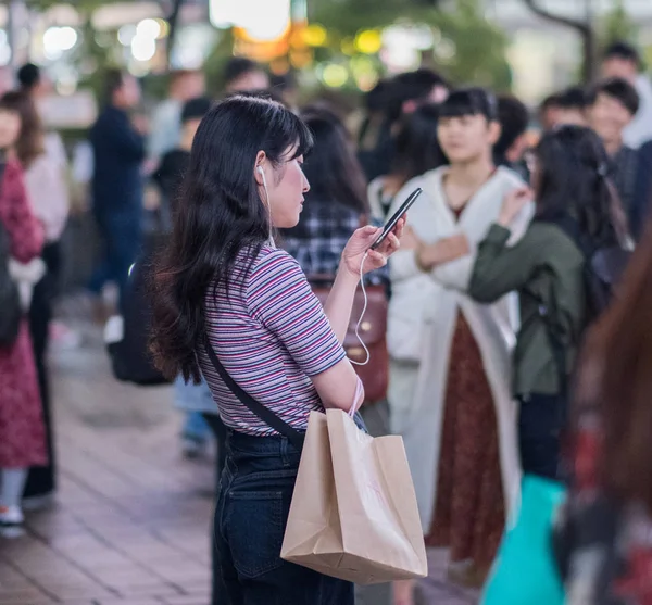 Tokyo, Japonya - 23 Haziran 2018. Hachiko Meydanı, Shibuya geceleri'akıllı telefon kullanan Japon kız.