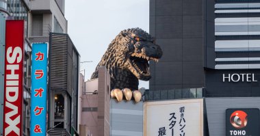 TOKYO, JAPAN - JUNE 30TH, 2018. Godzilla, popular Japanese pop cilture monster, overlooking a street in Kabukicho district, Shinjuku. clipart