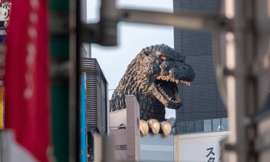 TOKYO, JAPAN - JUNE 30TH, 2018. Godzilla, popular Japanese pop cilture monster, overlooking a street in Kabukicho district, Shinjuku. clipart