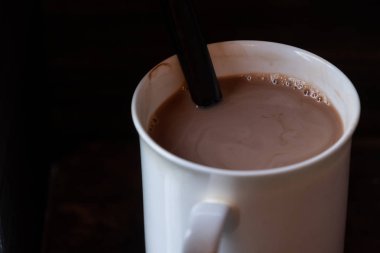 Ahşap arka plan üzerinde beyaz bir kupa sıcak çikolata