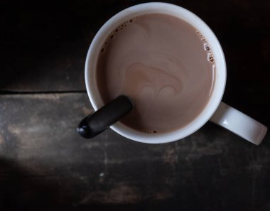 Ahşap arka plan üzerinde beyaz bir kupa sıcak çikolata