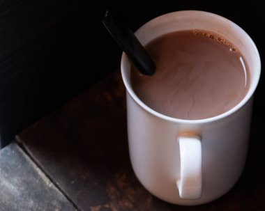 Ahşap arka plan üzerinde beyaz bir kupa sıcak çikolata