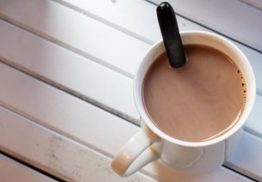 Ahşap arka plan üzerinde beyaz bir kupa sıcak çikolata