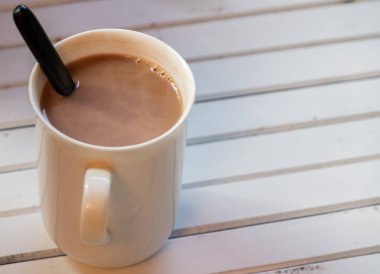 Ahşap arka plan üzerinde beyaz bir kupa sıcak çikolata