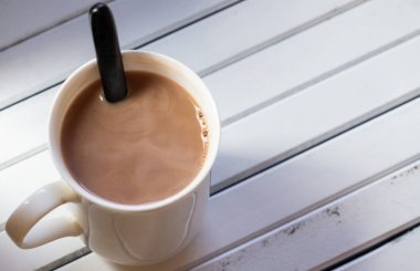 Ahşap arka plan üzerinde beyaz bir kupa sıcak çikolata