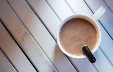 Ahşap arka plan üzerinde beyaz bir kupa sıcak çikolata