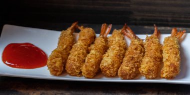 Ahşap arka plan üzerinde beyaz tabak içinde gevrek un kaplı derin kızarmış karides