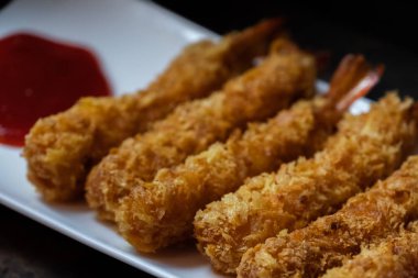 Ahşap arka plan üzerinde beyaz tabak içinde gevrek un kaplı derin kızarmış karides