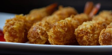 Ahşap arka plan üzerinde beyaz tabak içinde gevrek un kaplı derin kızarmış karides