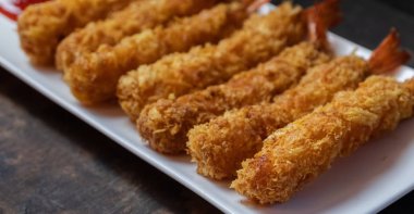 Ahşap arka plan üzerinde beyaz tabak içinde gevrek un kaplı derin kızarmış karides