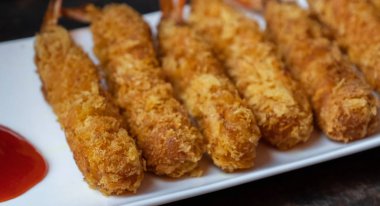 Ahşap arka plan üzerinde beyaz tabak içinde gevrek un kaplı derin kızarmış karides