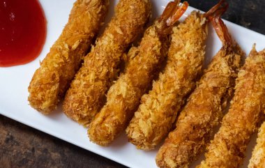 Ahşap arka plan üzerinde beyaz tabak içinde gevrek un kaplı derin kızarmış karides