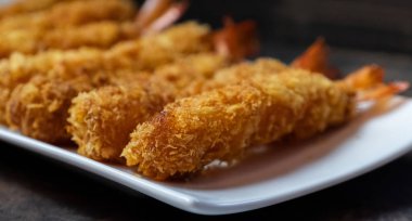 Ahşap arka plan üzerinde beyaz tabak içinde gevrek un kaplı derin kızarmış karides