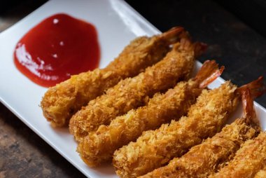 Ahşap arka plan üzerinde beyaz tabak içinde gevrek un kaplı derin kızarmış karides