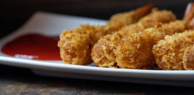 Ahşap arka plan üzerinde beyaz tabak içinde gevrek un kaplı derin kızarmış karides