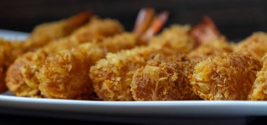 Ahşap arka plan üzerinde beyaz tabak içinde gevrek un kaplı derin kızarmış karides