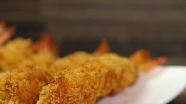 Ahşap arka plan üzerinde beyaz tabak içinde gevrek un kaplı derin kızarmış karides