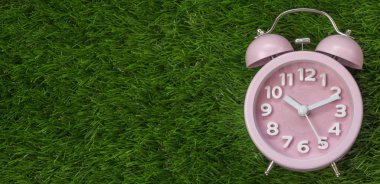 Çalar saat yeşil çimenlerin üzerinde pembe, yakın çekim