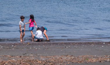 Tokyo, Japonya - 30 Nisan 2018. Enoshima Adası'nda bir plajda oynayan çocukları ile Japon baba