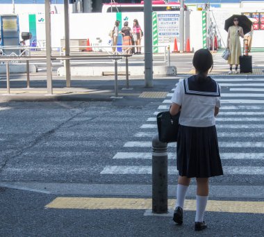 Tokyo, Japonya - 14 Temmuz 2018. Shibuya içinde karşıya okul üniformalı Japon kız.