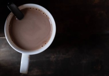 Ahşap arka plan üzerinde beyaz bir kupa sıcak çikolata
