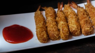 Ahşap arka plan üzerinde beyaz tabak içinde gevrek un kaplı derin kızarmış karides