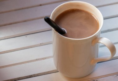 Ahşap arka plan üzerinde beyaz bir kupa sıcak çikolata