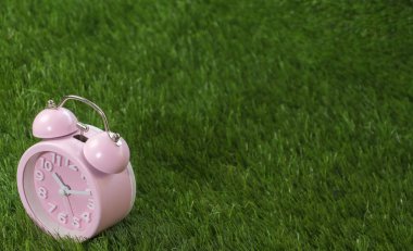 Çalar saat yeşil çimenlerin üzerinde pembe, yakın çekim