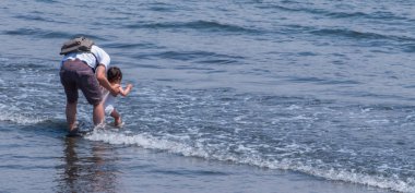 Tokyo, Japonya - 30 Nisan 2018. Enoshima Adası'nda bir plajda çocuğuyla oynayan baba 