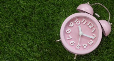 Çalar saat yeşil çimenlerin üzerinde pembe, yakın çekim