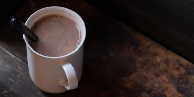 Ahşap arka plan üzerinde beyaz bir kupa sıcak çikolata