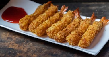 Ahşap arka plan üzerinde beyaz tabak içinde gevrek un kaplı derin kızarmış karides