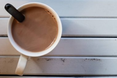 Ahşap arka plan üzerinde beyaz bir kupa sıcak çikolata