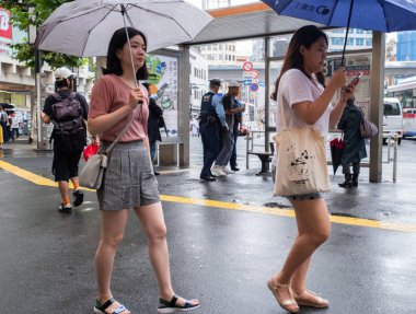 Tokyo, Japonya - 4 Temmuz 2018. Japon kadın şemsiye ile otobüs durağında yağmurlu gün boyunca, Shibuya yürüyüş
