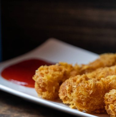 Ahşap arka plan üzerinde beyaz tabak içinde gevrek un kaplı derin kızarmış karides