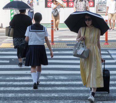 Tokyo, Japonya - 14 Temmuz 2018. Shibuya içinde karşıya okul üniformalı Japon kız.